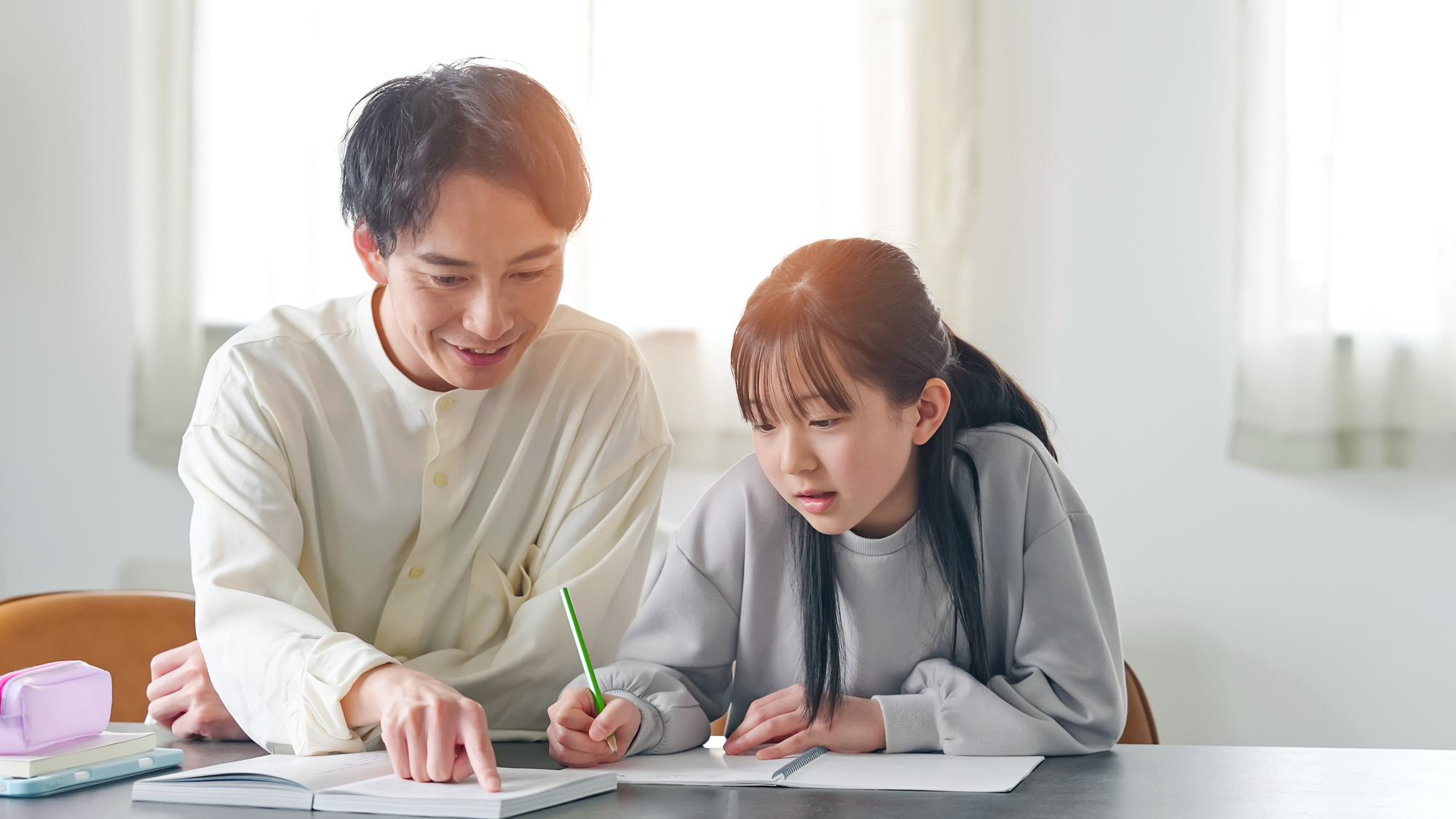 机に向かって学ぶ生徒と、隣で教える講師の手元