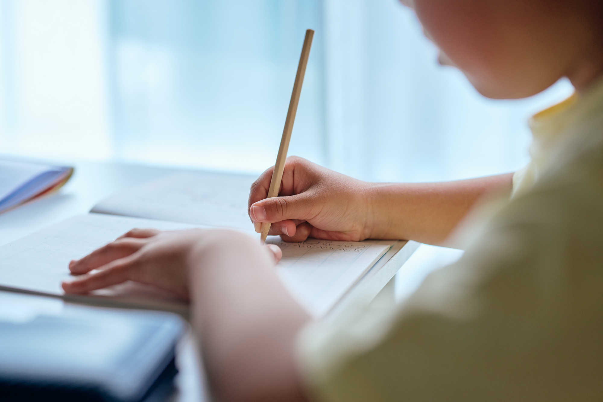 机に向かって学ぶ生徒と、隣で教える講師の手元